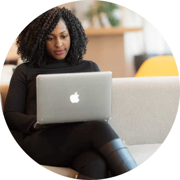 Une femme travaille sur un ordinateur portable assise sur un canapé.