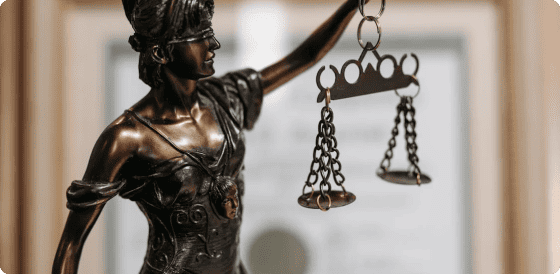 Statue de la justice tenant une balance devant un certificat encadré.